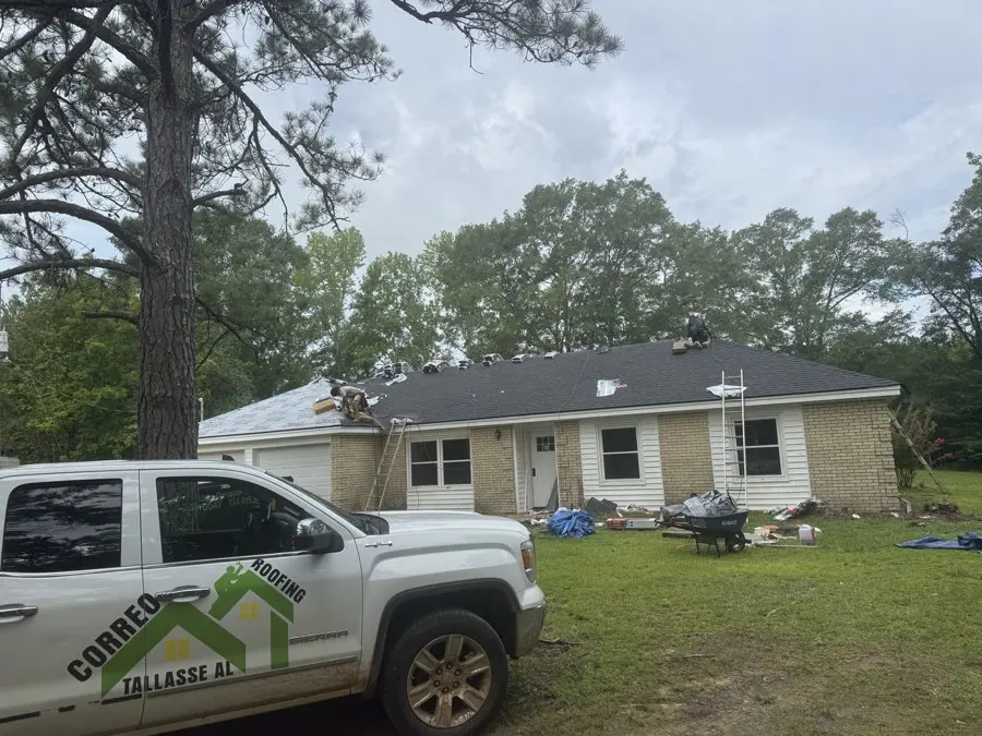 Brick house with a new dark shingle roof and a work truck out front