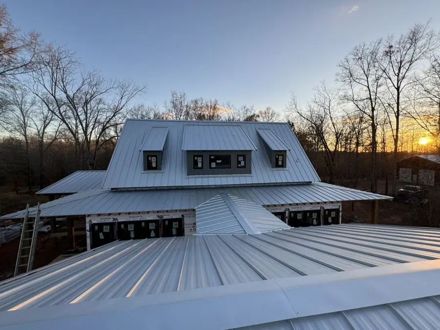 Standing-seam metal roof on a large house at sunset